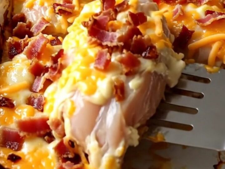 A golden, bubbling Creamy Bacon Cheddar Chicken Bake in a white ceramic dish on a rustic wood countertop.