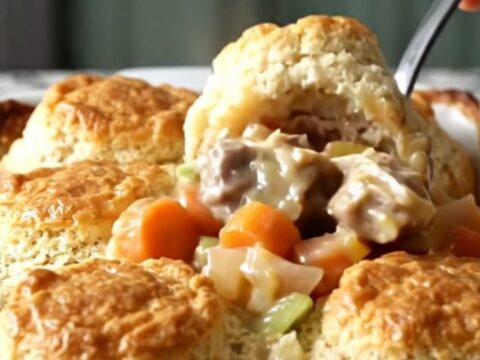 A golden, bubbling turkey and biscuit bake in a rectangular white ceramic dish on a speckled countertop.