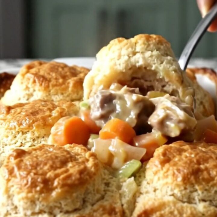 A golden, bubbling turkey and biscuit bake in a rectangular white ceramic dish on a speckled countertop.