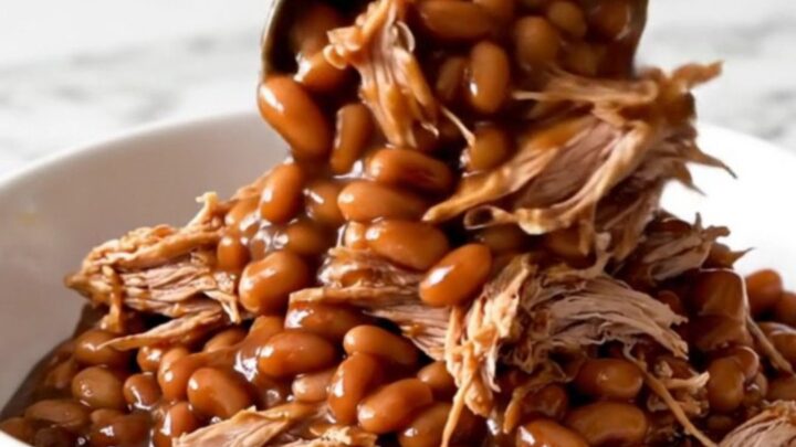 A close-up of tender shredded pork mixed with baked beans in a rich barbecue sauce.