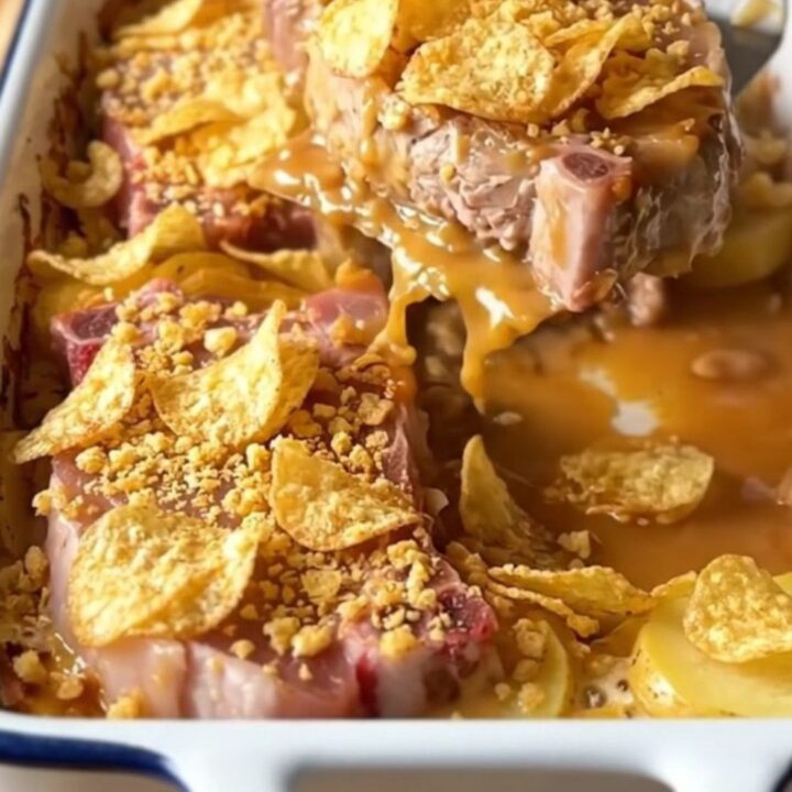 A top-down view of a rectangular baking dish filled with raw pork chops and sliced potatoes.
