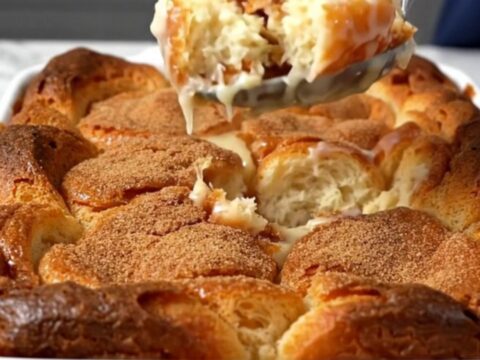 A top-down view of a rectangular baking dish filled with chunks of glazed donuts soaking in vanilla custard.