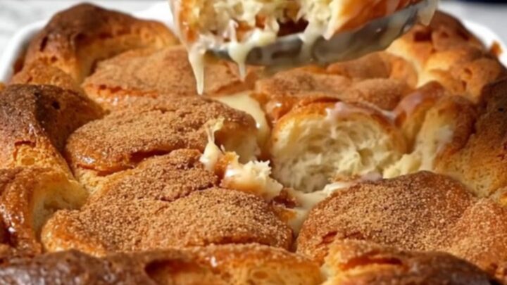 A top-down view of a rectangular baking dish filled with chunks of glazed donuts soaking in vanilla custard.