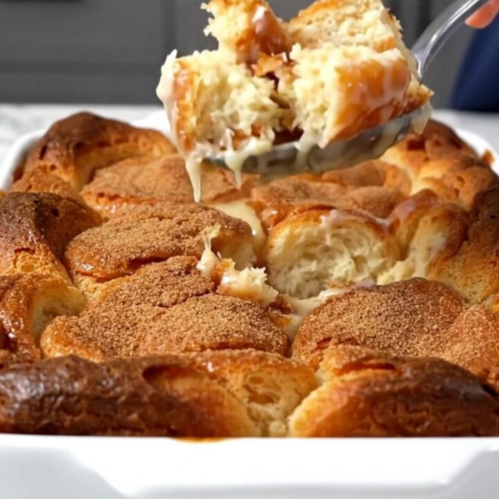 A top-down view of a rectangular baking dish filled with chunks of glazed donuts soaking in vanilla custard.