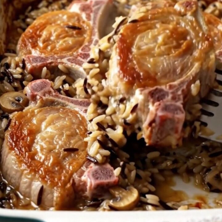 A golden-brown baked pork chop served over a bed of creamy wild rice in a white ceramic dish.