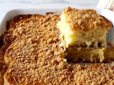 A golden brown, puffed eggnog French toast bake in a white ceramic dish on a speckled countertop.