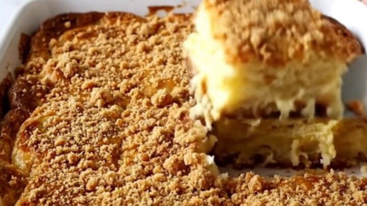 A golden brown, puffed eggnog French toast bake in a white ceramic dish on a speckled countertop.
