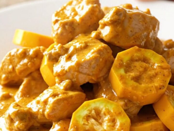 A warm, creamy chicken and yellow squash casserole served in a white bowl