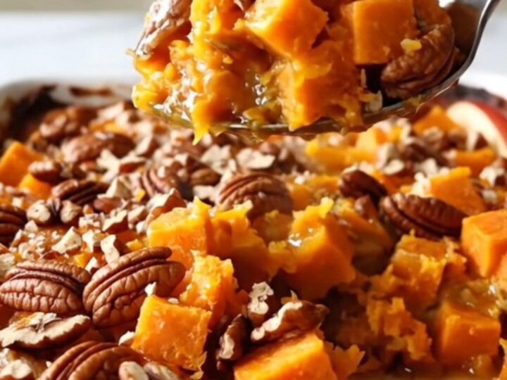 A large rectangular white baking dish filled with cubes of sweet potato and sliced red apples, topped with pecans.