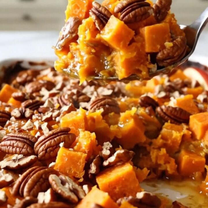 A large rectangular white baking dish filled with cubes of sweet potato and sliced red apples, topped with pecans.