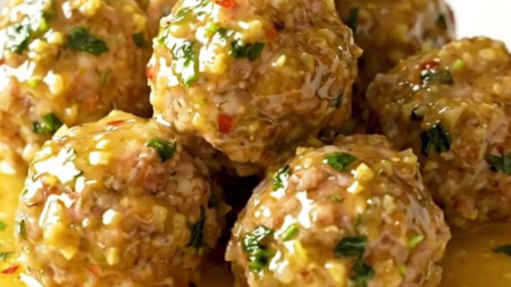 A close-up of tender turkey meatballs coated in a glossy golden garlic butter sauce with fresh parsley.