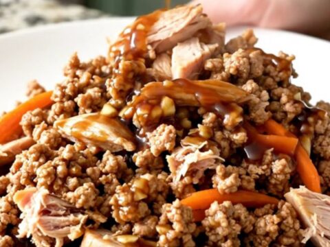 A close-up of tender Mongolian ground turkey with shredded carrots in a slow cooker, showing a rich, dark, and glossy sauce.
