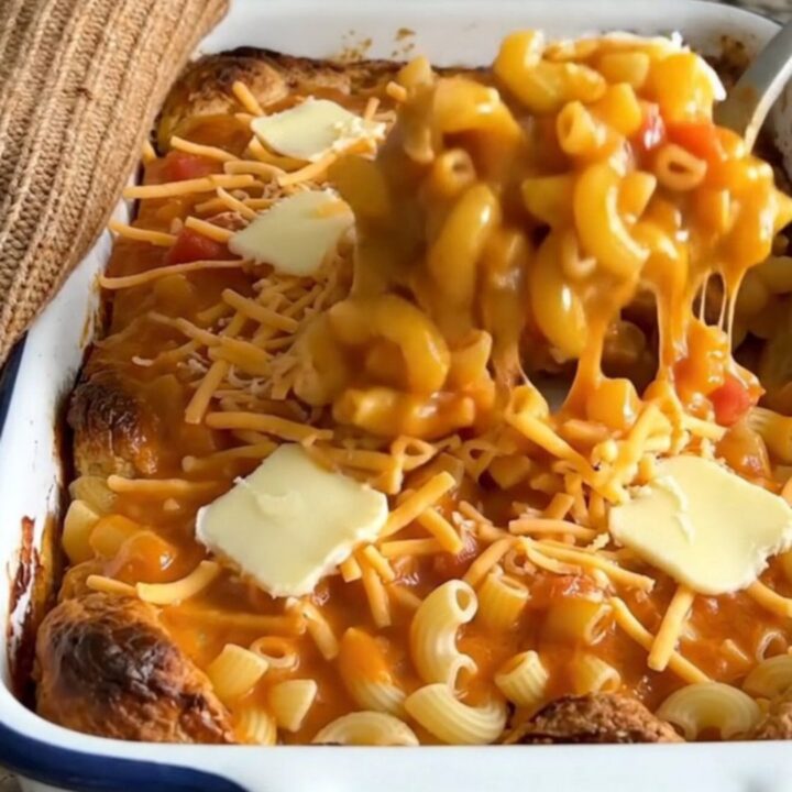 A large white enameled baker filled with golden, bubbling tomato mac and cheese on a granite countertop.
