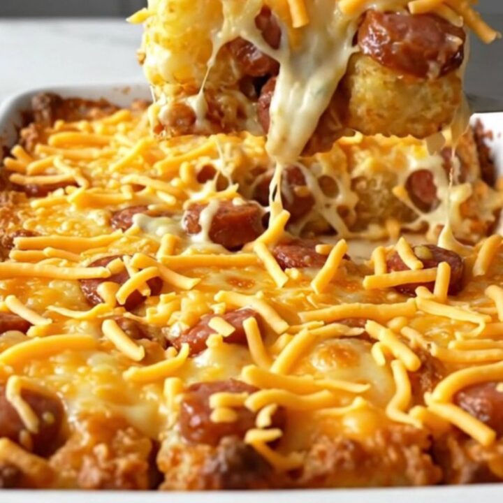 A golden-brown jalapeno popper smoked sausage tot casserole in a white ceramic dish.