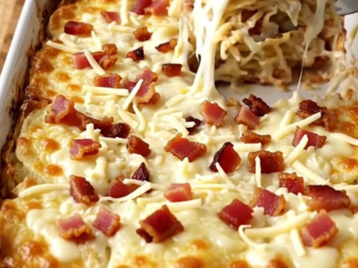 A golden, bubbling dish of scalloped potatoes with visible bacon bits and melted mozzarella cheese.