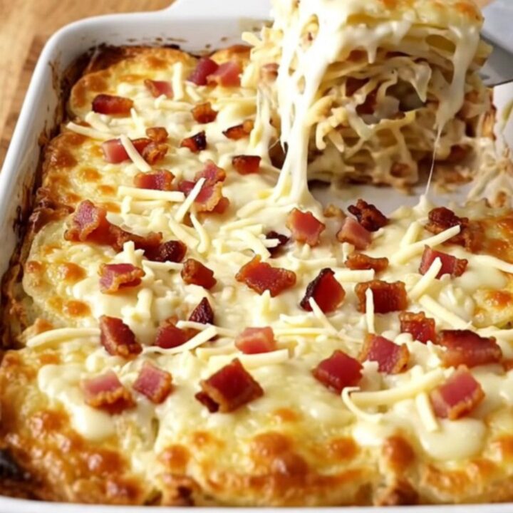 A golden, bubbling dish of scalloped potatoes with visible bacon bits and melted mozzarella cheese.