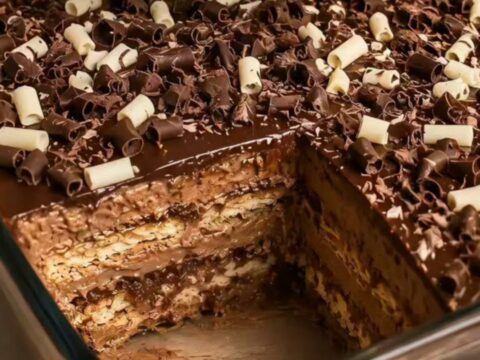 A tall slice of layered chocolate pavê showing distinct biscuit and creamy custard layers.