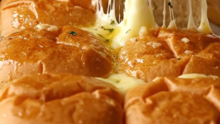 A rectangular baking dish filled with golden brown, buttery garlic grilled cheese sliders.