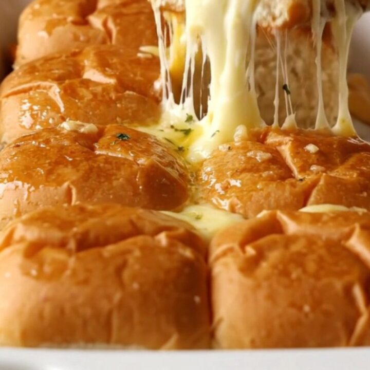 A rectangular baking dish filled with golden brown, buttery garlic grilled cheese sliders.