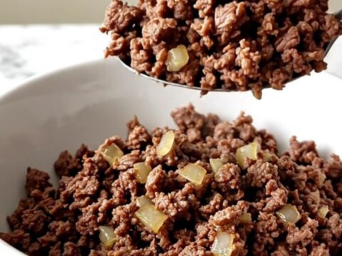 A close-up of a slow cooker filled with savory, cooked ground beef and onion mixture.
