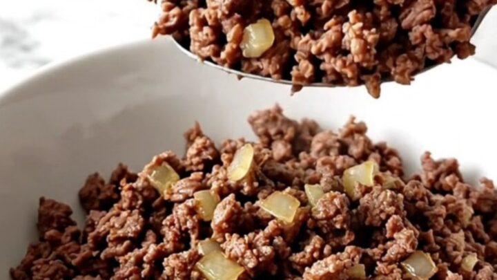 A close-up of a slow cooker filled with savory, cooked ground beef and onion mixture.