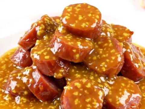 A slow cooker filled with golden, glazed kielbasa slices in an apricot Dijon sauce.