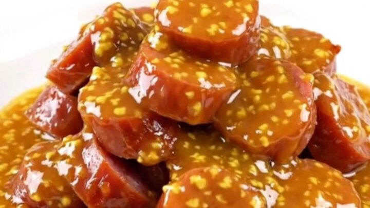 A slow cooker filled with golden, glazed kielbasa slices in an apricot Dijon sauce.