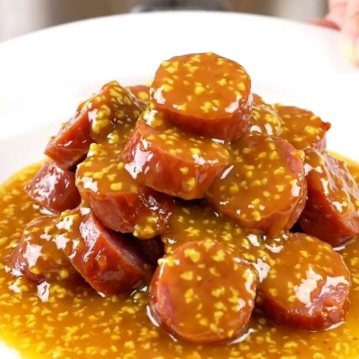 A slow cooker filled with golden, glazed kielbasa slices in an apricot Dijon sauce.