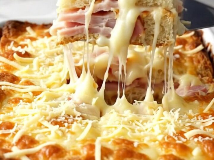 A golden, bubbling Monte Cristo breakfast casserole in a white ceramic dish.
