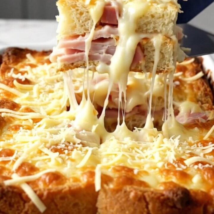 A golden, bubbling Monte Cristo breakfast casserole in a white ceramic dish.