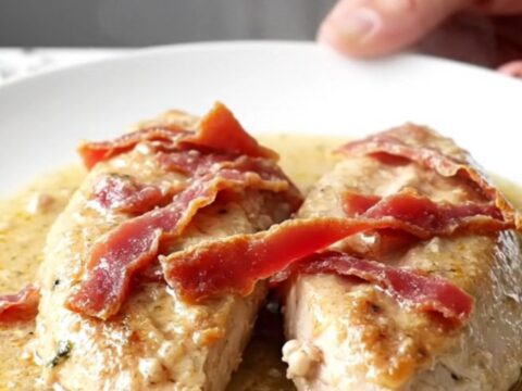 A close-up of tender chicken breasts covered in a creamy, savory sauce with thin slices of dried beef