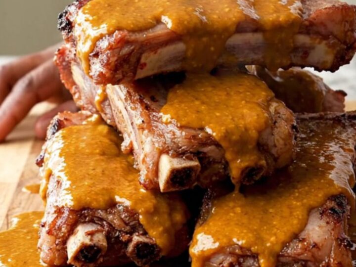A close-up of tender, slow-cooked buffalo baby back ribs on a wooden serving board.