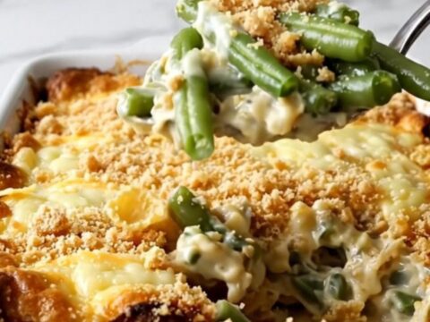 A vintage-style Swiss green bean casserole in a ceramic dish, topped with golden cornflakes and melted Swiss cheese.