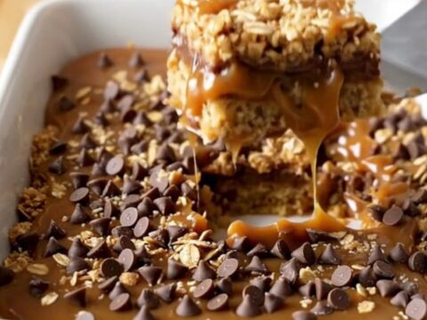 A top-down view of golden caramel oatmeal bars in a white rectangular ceramic baking dish.