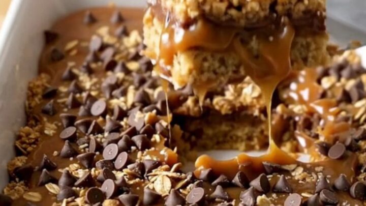 A top-down view of golden caramel oatmeal bars in a white rectangular ceramic baking dish.