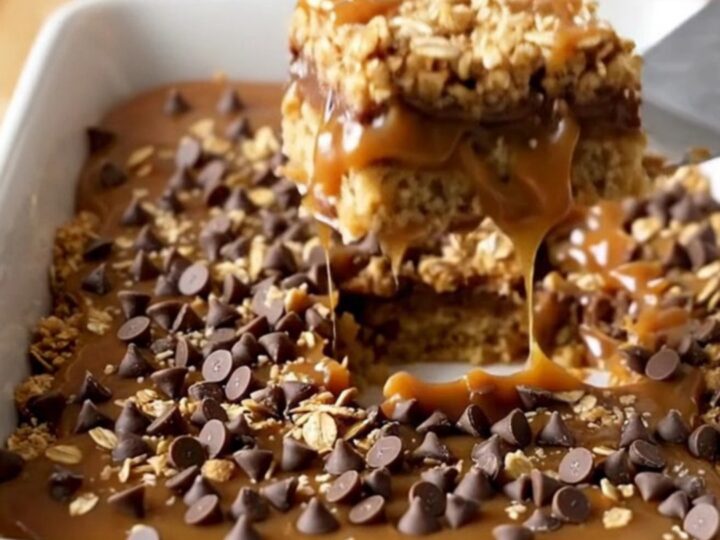 A top-down view of golden caramel oatmeal bars in a white rectangular ceramic baking dish.