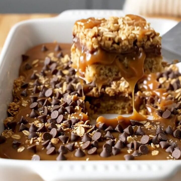 A top-down view of golden caramel oatmeal bars in a white rectangular ceramic baking dish.