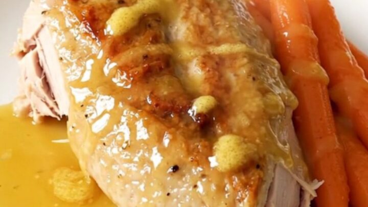 A whole boneless turkey breast and baby carrots in a slow cooker with a honey butter glaze.