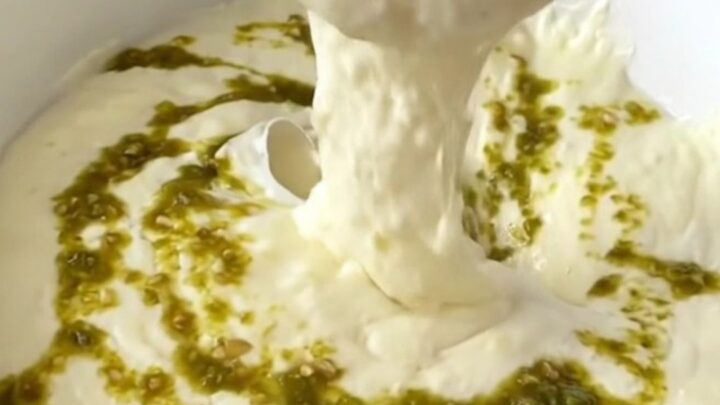 A close-up of thick, melted white queso in a black slow cooker, ready to be served at a party.