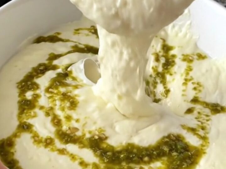 A close-up of thick, melted white queso in a black slow cooker, ready to be served at a party.