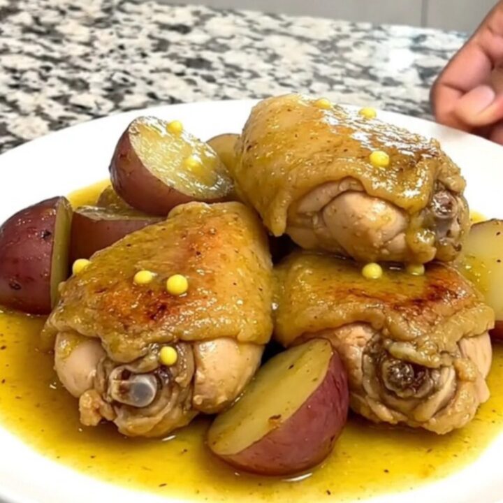 Slow cooker garlic Dijon chicken and red potatoes served in a shallow bowl with sauce.