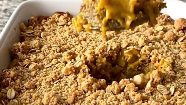 A large rectangular ceramic dish filled with golden-brown pumpkin pie crisp on a speckled granite countertop.