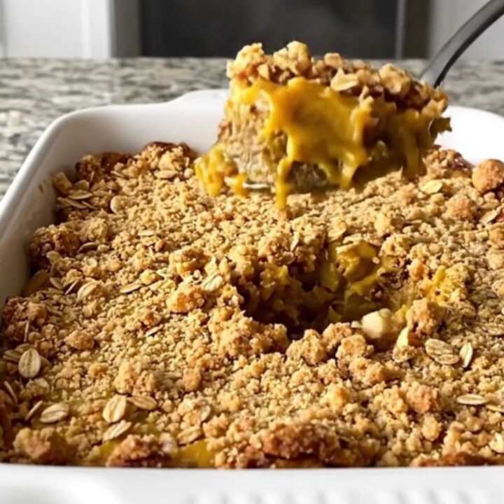 A large rectangular ceramic dish filled with golden-brown pumpkin pie crisp on a speckled granite countertop.