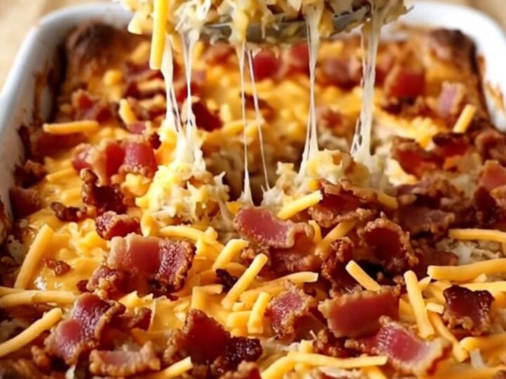 A golden, bubbling pimento cheese hash brown casserole fresh out of the oven in a rectangular white baking dish.