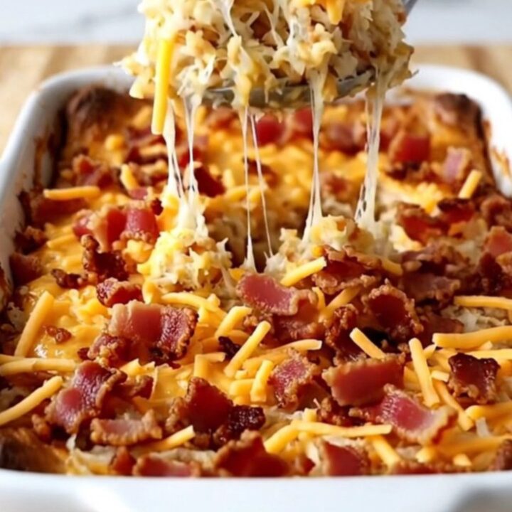 A golden, bubbling pimento cheese hash brown casserole fresh out of the oven in a rectangular white baking dish.