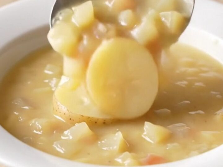 A bowl of creamy potato au gratin soup with visible potato slices and melted cheddar cheese.