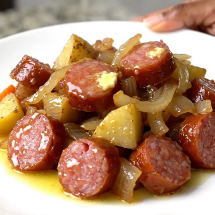 A close-up view of the slow cooker filled with sliced smoked sausage, cubed potatoes, carrots, and onions.