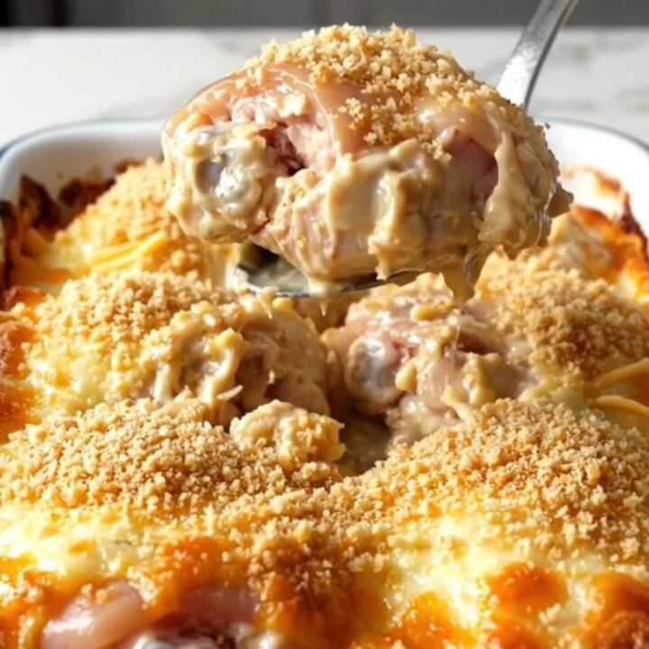 A golden, bubbling cheesy garlic bread chicken bake in a rectangular white enameled dish.