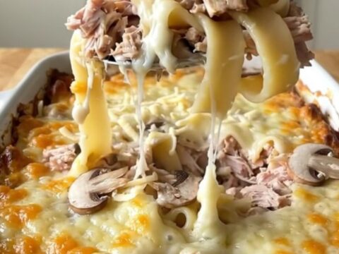 A top-down view of a golden, bubbling Mushroom Swiss Turkey Noodle Bake in a white ceramic dish.