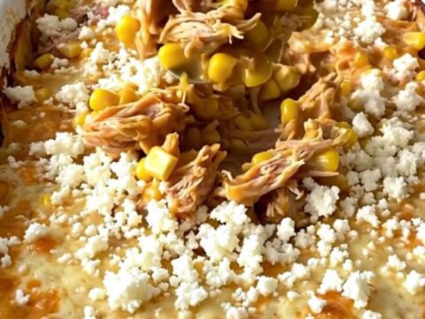 A top-down view of a golden, bubbling Mexican street corn turkey casserole in a white enamel baker.